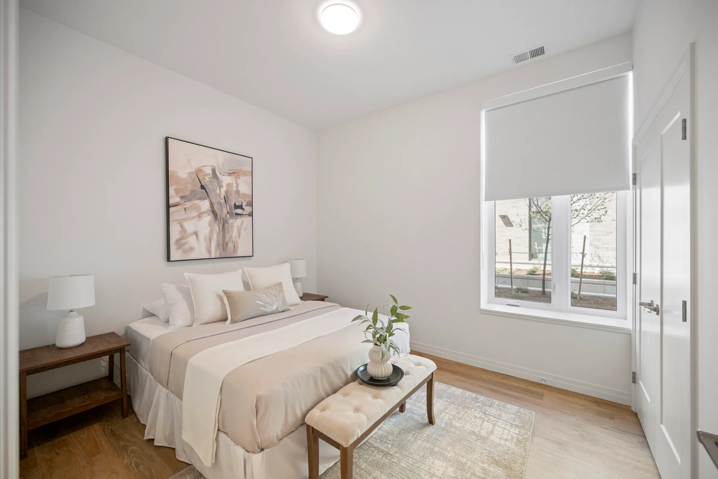 Bedroom with a wide window and pale bedding